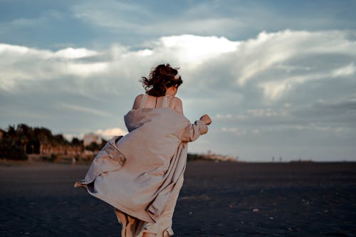 Free A Woman Wearing a Coat Walking on the Sand Stock Photo