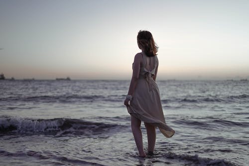 Woman in Brown Dress Standing on the Sea