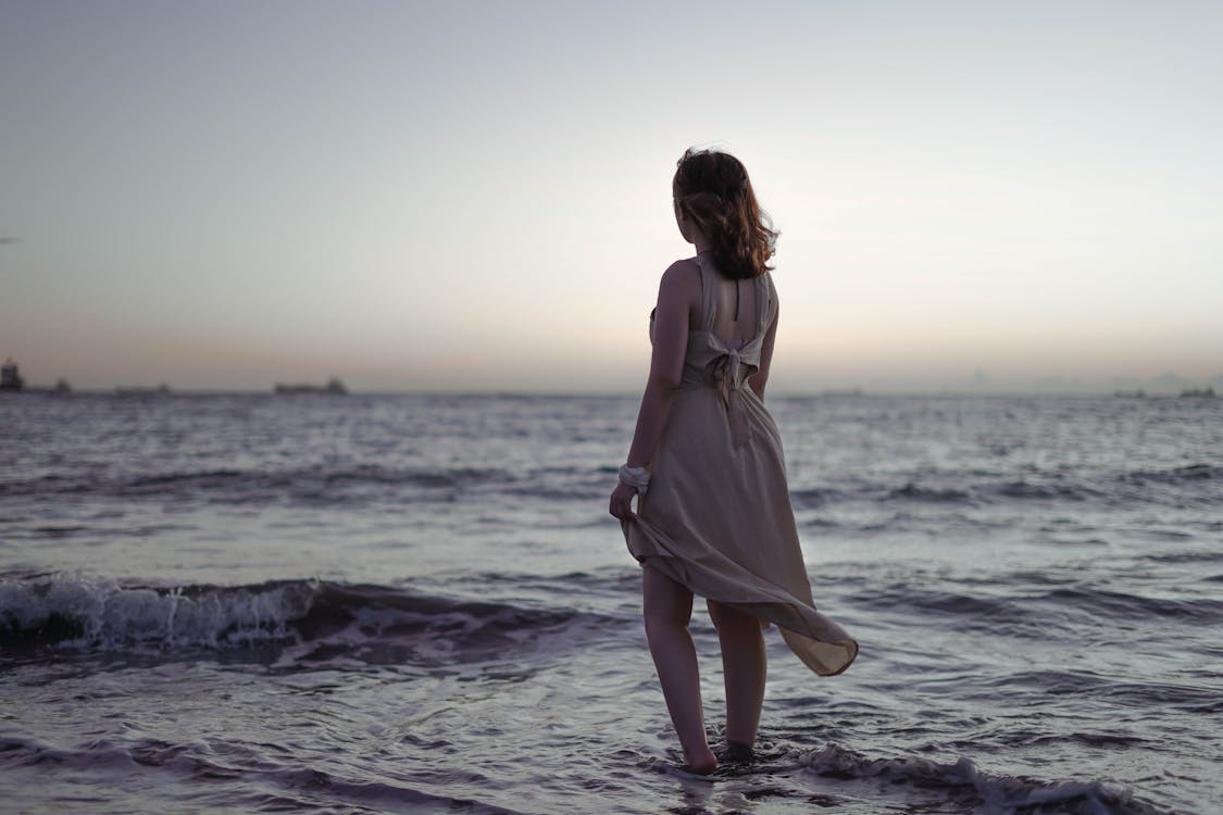 Woman in Brown Dress Standing on the Sea