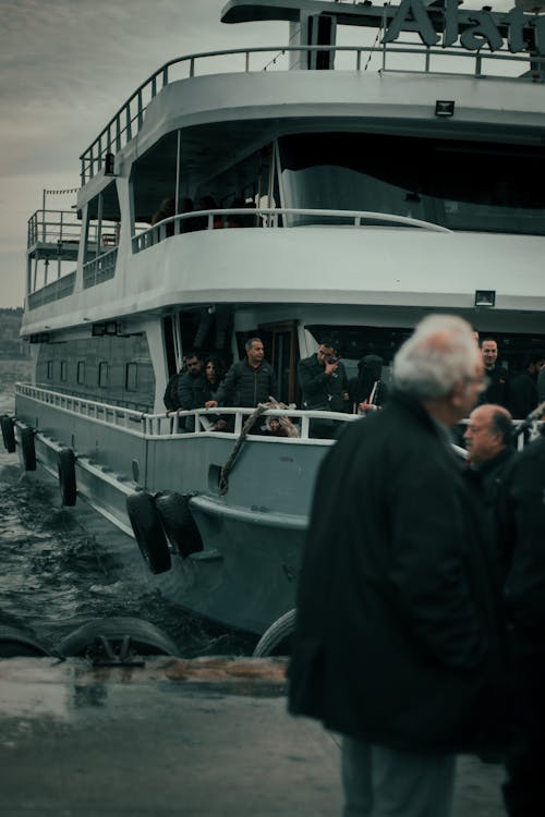 Group of people on wet pavement and big white three storey boat in seaport in autumn