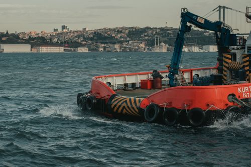 Free Modern big black crane and wheels on ship in bay next to settlement on mountain slope Stock Photo