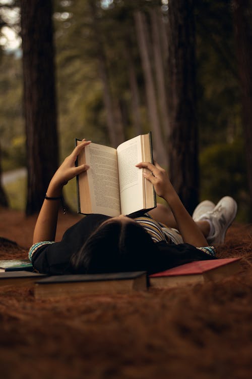 Free Woman Lying on Grass Reading a Book  Stock Photo
