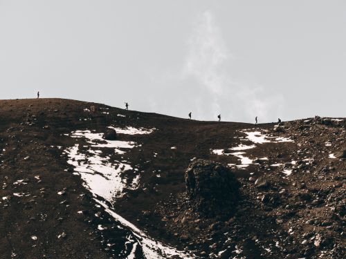 Free Group of hikers on a remote snow-covered mountain trail under a cloudy sky. Stock Photo