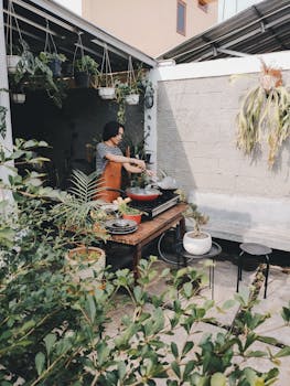Asian chef cooking outdoors in a lush garden setting. Perfect for lifestyle and culinary themes.