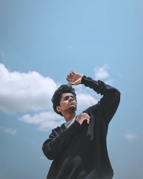 身穿黑色毛衣的男子扬起手臂，仰望天空，自信而个性十足