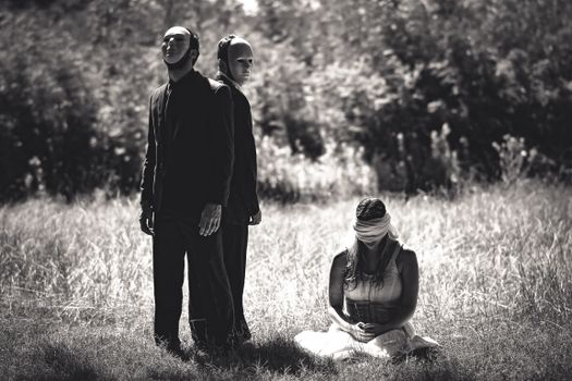 Men in Face Masks Standing Over Blindfolded Woman
