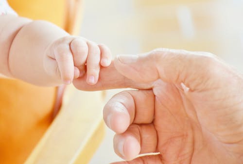 Person Touching Hand of Baby