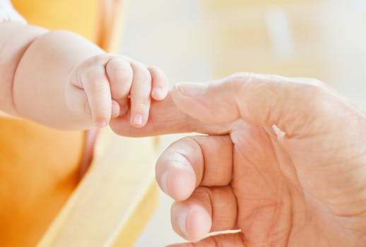 Person Touching Hand of Baby