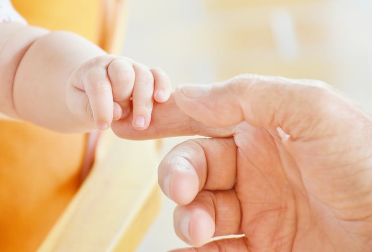 Person Touching Hand Of Baby