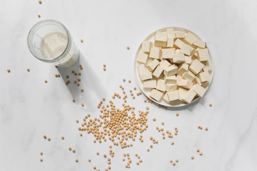 Top view of tofu cubes, soybeans, and soy milk on a white background – perfect for vegan food themes.