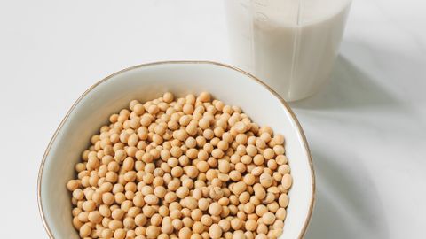 A bowl of soybeans and a glass of soy milk on a white background, ideal for health and nutrition themes.