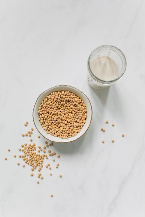 Top View Photo of Soybeans on Bowl Near Drinking Glass With Soy Milk