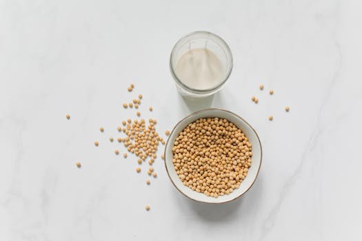 High-angle view of soybeans in a bowl and a glass of soy milk on a marble background.