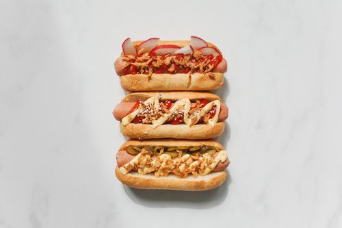 Free Delicious gourmet hot dogs with various savory toppings on a white background. Stock Photo