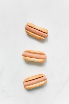 Three plain hot dogs arranged in a minimalist fashion on a white background.