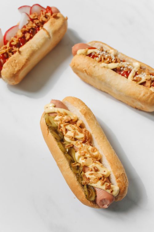 Free Three gourmet hot dogs with various toppings on a white background. Stock Photo