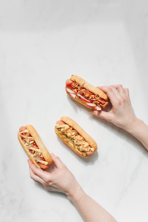 Person Holding Hotdog Sandwiches