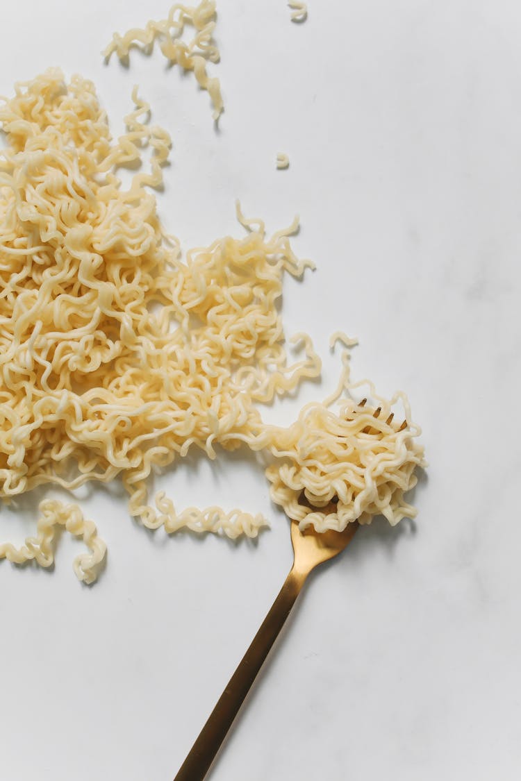 Pasta And Gold Fork On White Surface