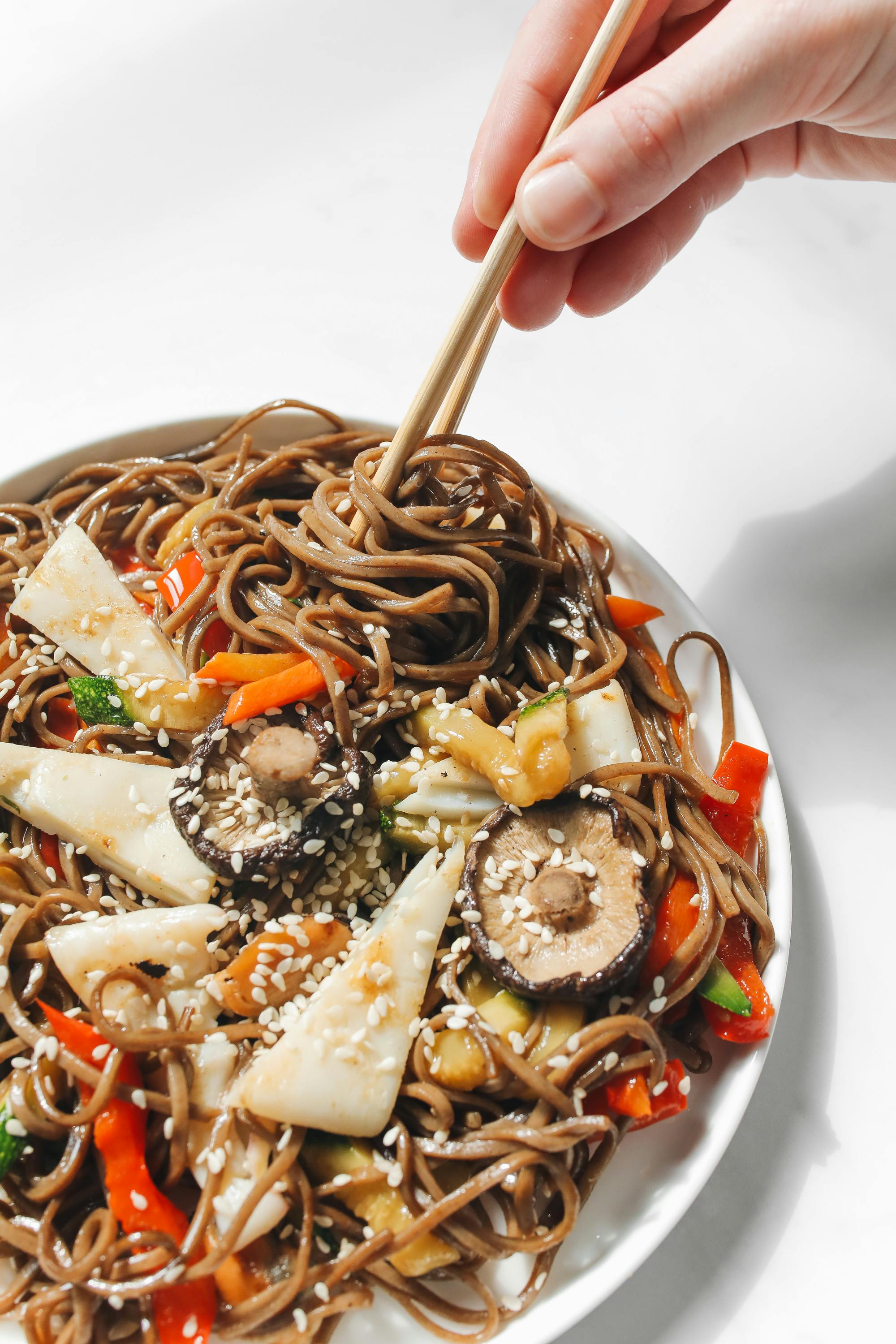 brown noodles and vegetables on white ceramic plate