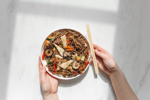 Person Holding Plate With Noodle Dish and Chopstick