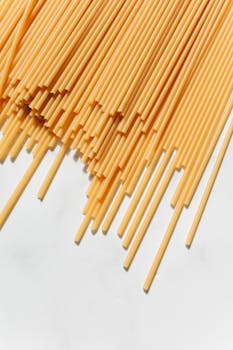 A detailed close-up of uncooked spaghetti on a white surface, showcasing texture and color.