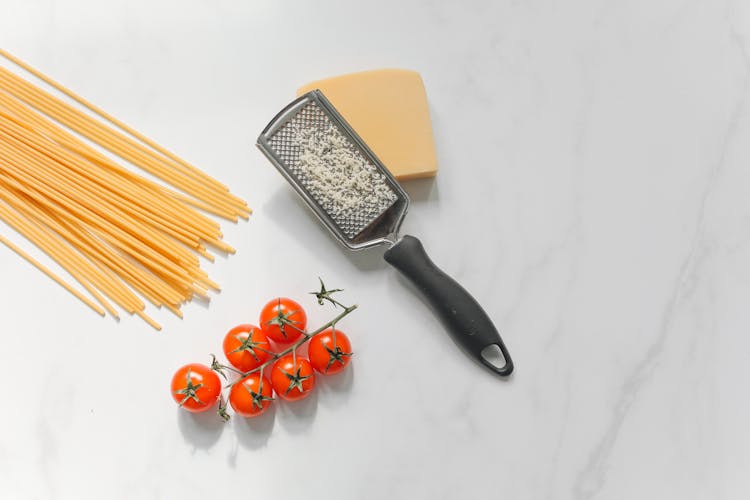 Cheese With Grater Beside Spaghetti And Tomatoes