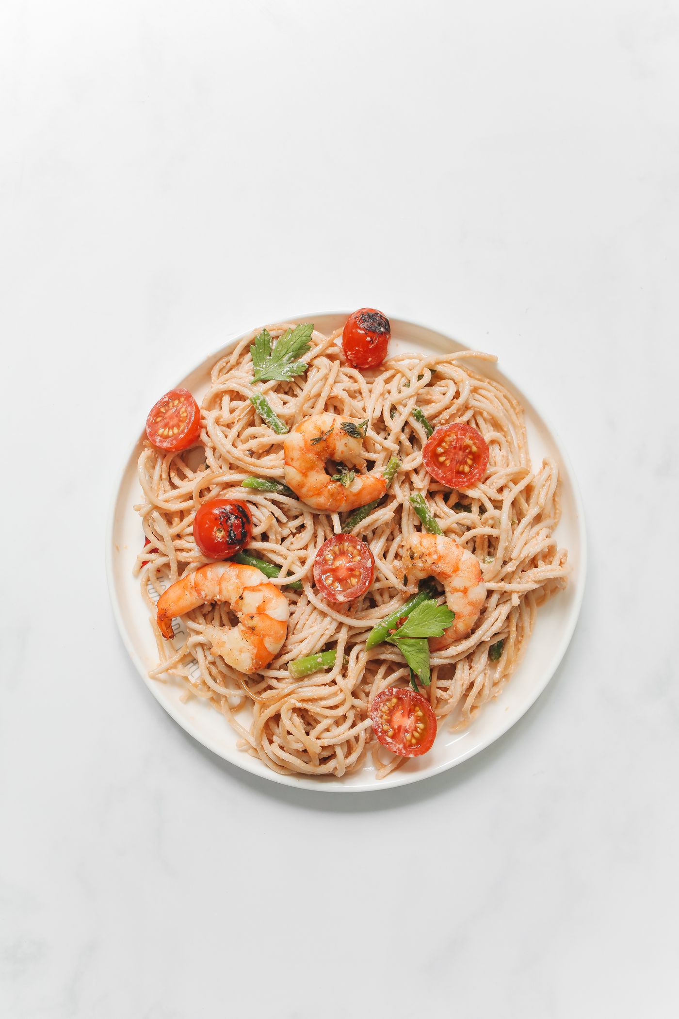 Spaghetti con gamberi e pomodorini in un piatto bianco
