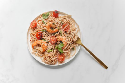 Appetizing shrimp pasta with cherry tomatoes on a white plate, perfect for Italian cuisine enthusiasts.