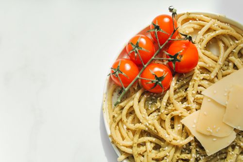 Free Fresh cherry tomatoes and parmesan cheese adorn this delicious vegetarian pesto pasta. Stock Photo