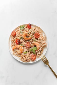 An appetizing plate of shrimp pasta with cherry tomatoes and herbs. Perfect for dinner.
