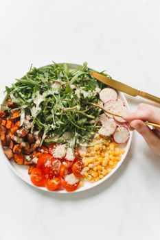 A vibrant salad with arugula, cherry tomatoes, radish, and corn, perfect for a healthy meal.