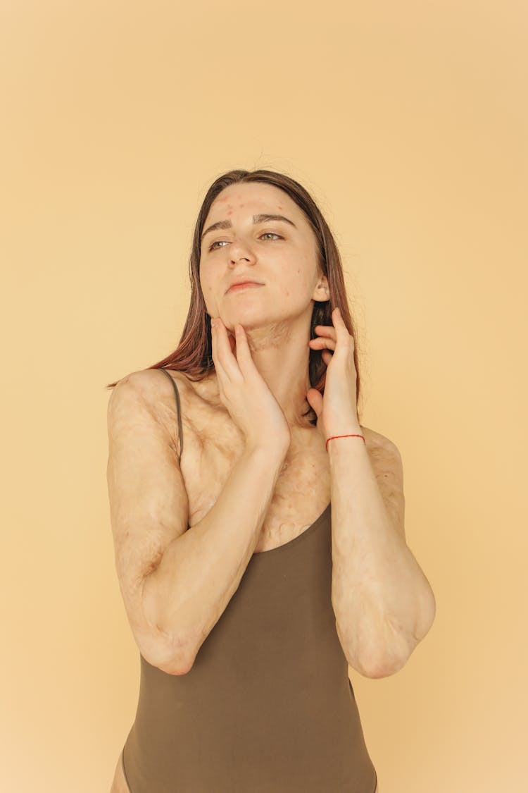 A Woman In Brown Tank Top With Her Hands On Her Neck