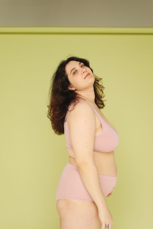Free Confident plus-size woman posing against a green background, embracing body positivity. Stock Photo