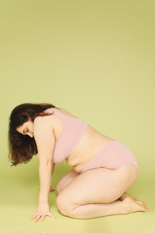 Free A plus size woman poses in pink lingerie against a soft green background. Stock Photo