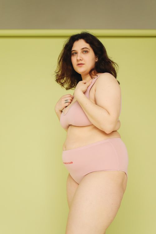 Free Confident woman posing in studio shoot with green background wearing pink underwear. Stock Photo