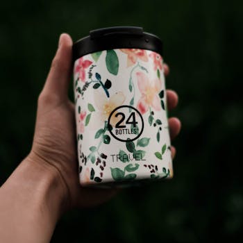 A hand holding an eco-friendly floral design travel bottle, perfect for sustainability enthusiasts.
