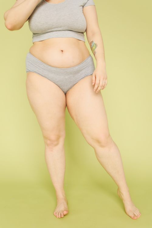 Free Portrait of a plus-size woman embracing body positivity in a studio setting. Stock Photo