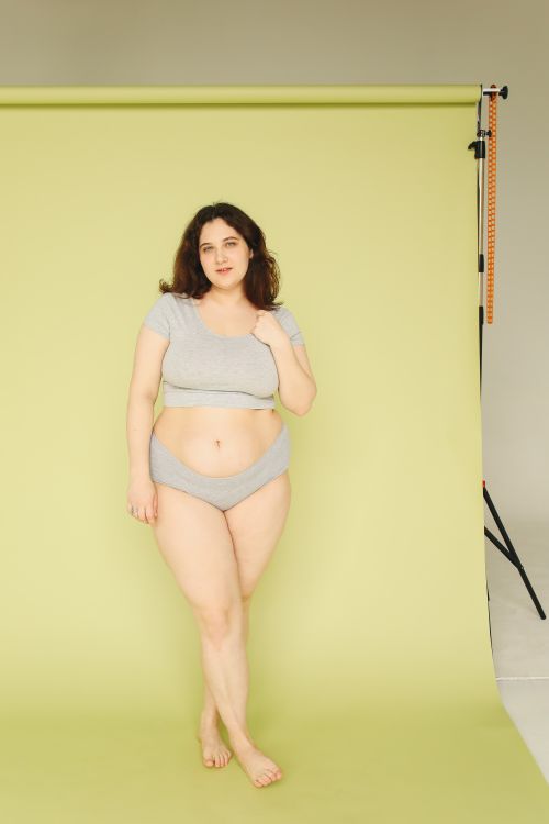 Free Plus size woman posing confidently in studio with green background, embracing body positivity. Stock Photo