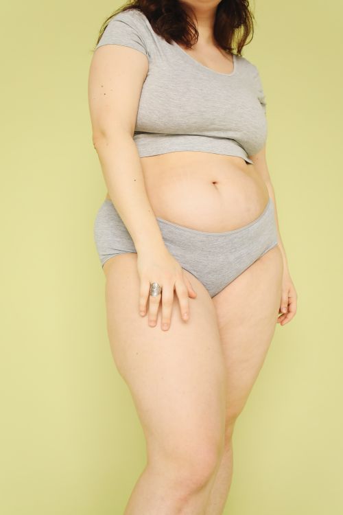 Free Empowering studio portrait of a plus-size woman embracing body positivity in a gray outfit. Stock Photo