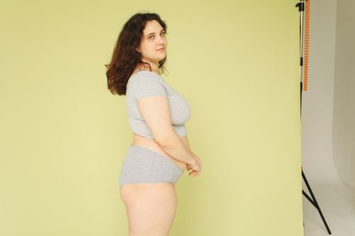 Free Portrait of a confident plus size woman posing in a studio with a yellow background. Stock Photo