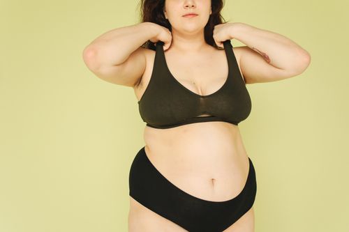 Free A confident plus size woman poses in underwear against a yellow background, embracing body positivity. Stock Photo