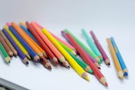 白色桌面上散落着彩色铅笔的特写镜头，非常适合艺术项目