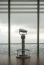 Modern stationary city binoculars near glass wall of high building to observe contemporary cityscape