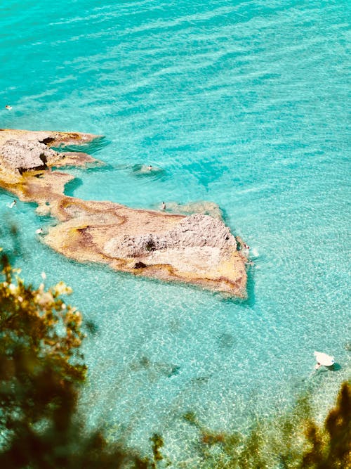 From above of people in bright water in turquoise rippling sea in lagoon