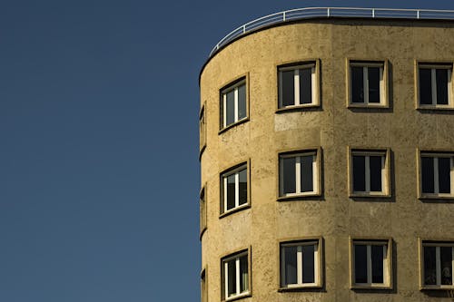 Glass Windows of Brown Concrete Building Under Blue Sky
