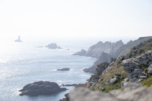Free Stunning view of the rocky coastline and sea from Pointe du Raz, featuring a distant lighthouse. Stock Photo