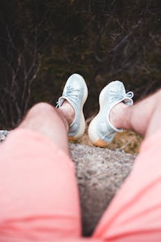 A man in shorts relaxes on a rocky cliff edge, enjoying nature and serenity.