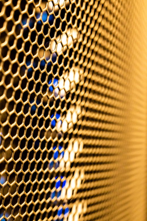 Closeup of gold net wall with shiny surface made of metal placed in row in modern room of contemporary studio
