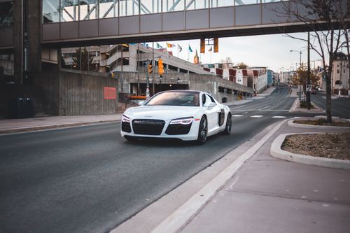 Free White automobile driving near intersection with crosswalk on city street near small houses during summer time in modern downtown in evening Stock Photo