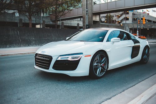 Automobile with contemporary design riding on narrow asphalt route near metal construction during trip in city street in evening time